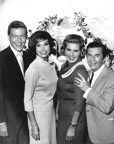 four people posing for the camera in front of a tree