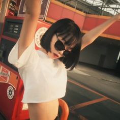 a woman in short shorts and knee high boots standing next to a red gas pump