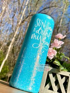 a blue spray can sitting on top of a wooden table next to flowers and trees