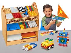 a young boy holding a wooden toy box with construction vehicles and building blocks in it