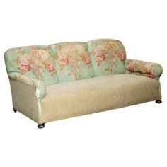 a couch that is sitting on top of a wooden frame and has flowers on it