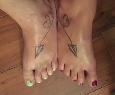 two people with tattoos on their feet standing next to each other, one has an arrow and the other has a heart