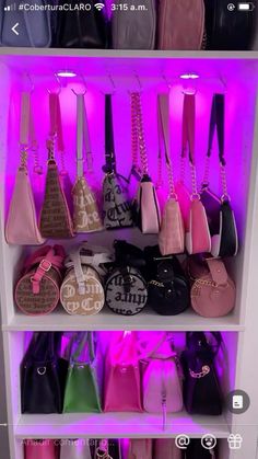 a shelf filled with lots of purses on top of each other in front of a purple light