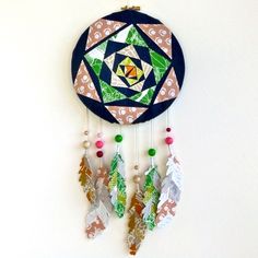 a decorative wall hanging made out of fabric and paper with beads on the sides, featuring an ornament