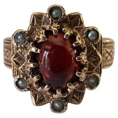 This beautiful antique Victorian ring features a natural oval-shaped cabochon garnet accented by six seed pearls set in an ornate band with fine hand engraving fashioned from 14K yellow gold. The markings on the band indicate the ring was most likely manufactured in Europe. Circa late 19th century. Antique Rings Victorian Silver, Vintage Art Deco Ring, Victorian Engagement Ring Antique, Antique Engagement Rings Victorian, Ruby Gold Ring, Victorian Wedding Ring, Antique Rings Victorian, Victorian Style Rings, Natural Pearl Ring