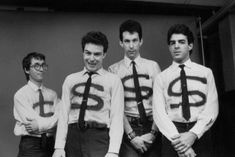 four young men wearing ties with the letters $ on them, standing in front of a wall