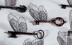 several antique keys are lined up on a white sheet with wire leaves attached to them