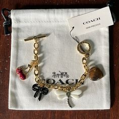 Coach Mixed Charm Toggle Bracelet Semi- Precious Stone Hear, Cherry, Bow. New With Tags! Refined Chain Link Bracelet Colorful Mixed Charms Including A Semi-Precious Stone Heart, Black Bow, Dragonfly And Enamel Cherries Brass/Glass/Enamel Set In Polished Gold-Tone Metal Easy Toggle Closure Includes Coach Pouch Approx. 7" L X 0.2" W; Charm Drop: 0.5 -0.75"; Depth: 0.25" Jewelry Must Haves, Coach Charms, Coach Pouch, Custom Charm Bracelet, Coach Jewelry, Vintage Charm Bracelet, Jewelry Accessories Ideas, Gold Charm Bracelet