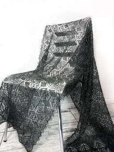 a chair covered in black lace sitting on top of a wooden floor