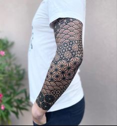 a man with a tattoo on his arm is standing in front of a flower of life