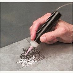 a person is using a pen to draw designs on a piece of paper with scissors