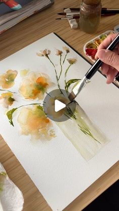 someone is painting flowers on a canvas with watercolors