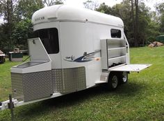 a white trailer parked on top of a lush green field