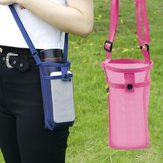 a woman is holding a pink bag in the grass with her camera attached to it