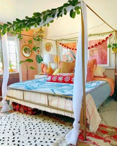 a canopy bed with pillows and blankets on it in a room that has pink walls