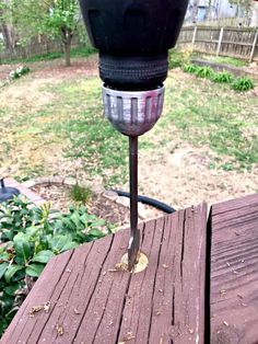 a close up of a parking meter on a wooden deck in a yard with grass and trees