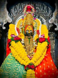 an idol sitting on top of a chair covered in yellow and red flowers next to a wall