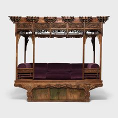 an old wooden bed with purple sheets on it's sides and canopy over the top