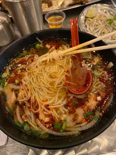 a wok filled with noodles and vegetables on top of a table