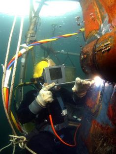 a man in scuba gear is holding up a camera and looking at something under the water