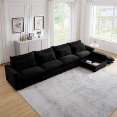 a large black sectional sofa sitting on top of a hard wood floored living room