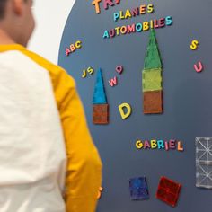 a man standing in front of a wall with magnets on it