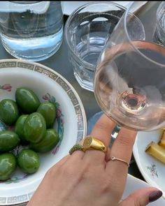 a woman is holding a wine glass in front of some green peppers and lemons