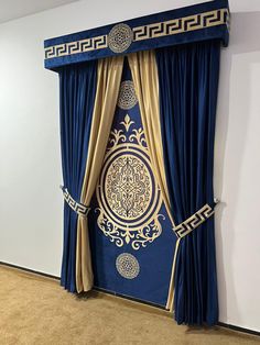 a blue and gold curtain in front of a white wall with an intricate design on it