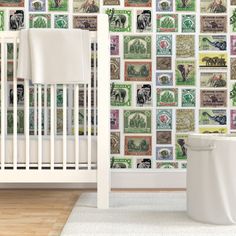 a white crib in front of a wall with stamps on it and a baby's bed