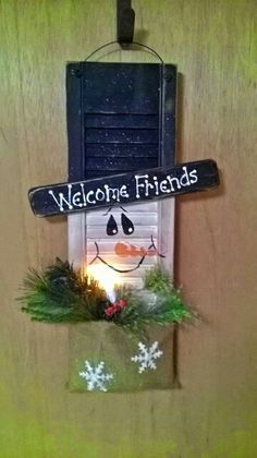 a welcome sign hanging from the side of a wooden door with snowflakes on it