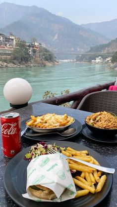 two black plates with food on them sitting on a table next to a red can