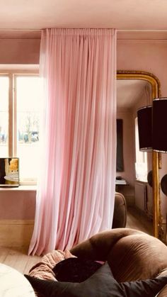 a living room with pink drapes hanging from the ceiling and a mirror on the wall