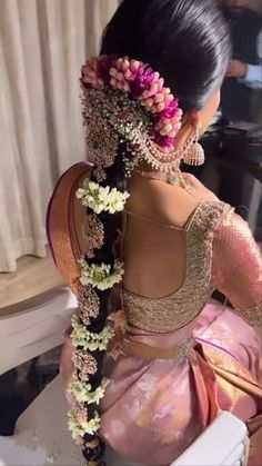 a woman with flowers in her hair sitting on a chair