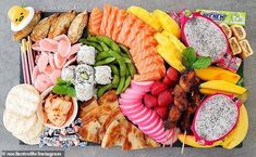 an assortment of fruits, meats and vegetables on a platter with chopsticks