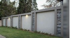 a long wall with lights on it next to a grass area and trees in the background