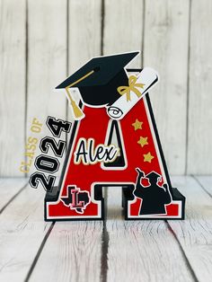 a red and black letter shaped like a graduation cap with the word alex on it