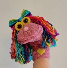 a hand holding a stuffed animal with colorful hair