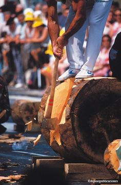 a man standing on top of a log with a wooden mallet in his hand