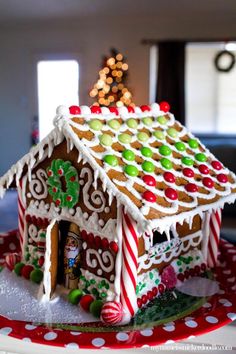 a gingerbread house decorated with candy canes and candies on a red plate