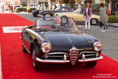 an old fashioned car is parked on the red carpet