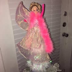 a barbie doll is standing on top of a christmas tree in front of a door