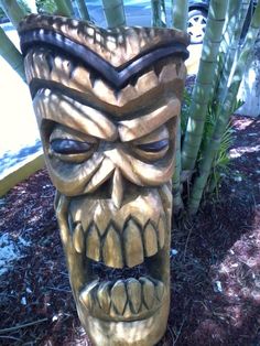 a wooden mask sitting next to a bamboo tree