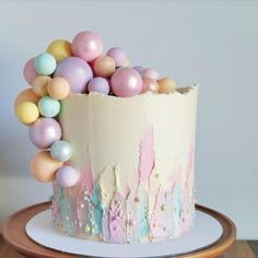 there is a cake decorated with pastel colors and balloons on the top of it