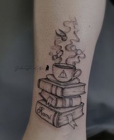 a tattoo on the leg of a woman with books and a cup