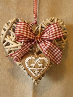 a heart shaped ornament hanging on a wall next to a wooden stick and ribbon