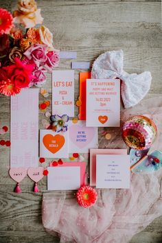 the wedding stationery is laid out with flowers and paper hearts on top of it