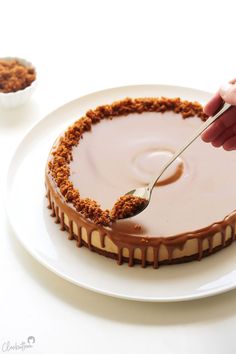 a person is spreading icing onto a cake on a plate with a fork and spoon