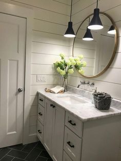 a bathroom with two sinks and a large round mirror