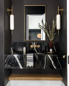 a bathroom with black marble counter tops and gold accents