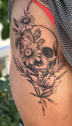 a woman's thigh with a skull and flowers on it